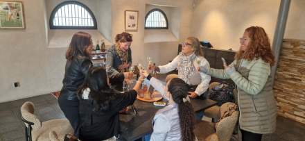 Dégustation conviviale autour d’une table avec verres de vin et bouteilles en arrière-plan, ambiance chaleureuse – Fayet Hospitality