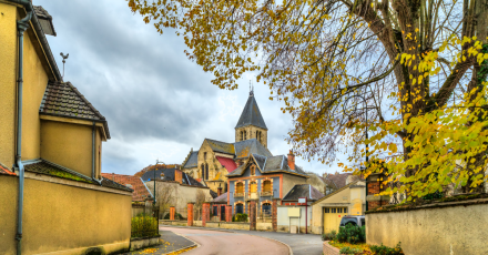 Vue pittoresque du village de Poligny avec son église au centre, maisons traditionnelles et arbres aux couleurs automnales, dans le Jura – Fayet Hospitality