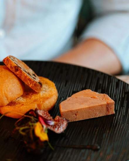 Assiette gastronomique avec tranche de foie gras, pain grillé et garniture décorative sur une table élégante – Fayet Hospitality