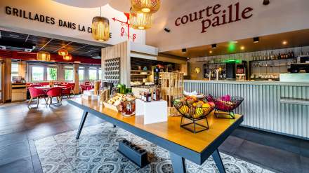 Buffet du restaurant Courtepaille de l’Hôtel Ibis Reims Tinqueux, avec fruits frais, viennoiseries, confitures et bar en arrière-plan dans un décor lumineux et chaleureux.