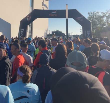 Participants rassemblés au départ d’une course sportive sous un portique noir, Fayet Hospitality.