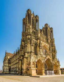 Façade gothique de la cathédrale Notre-Dame de Reims sous un ciel bleu clair.