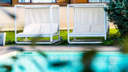 Transats modernes avec voilages blancs installés en bord de piscine dans un espace extérieur lumineux.