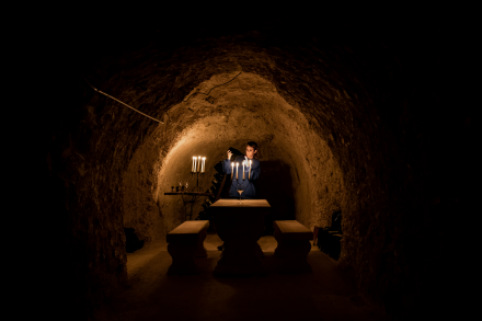 Table en pierre avec bougies allumées dans une cave voûtée éclairée à la lueur des chandelles, ambiance intimiste et authentique - Fayet Hospitality