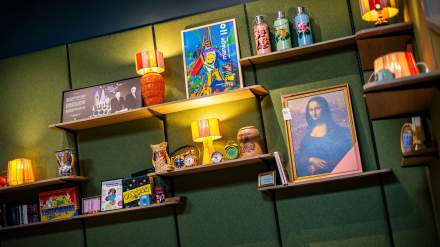 Étagères décoratives du greet hôtel Reims Tinqueux, ornées de lampes rétro, objets vintage, livres, affiches colorées et reproduction encadrée de la Joconde.