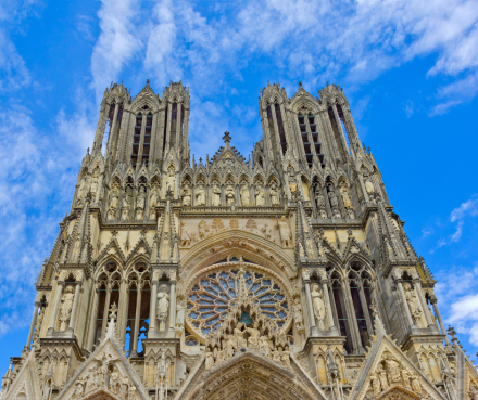 Façade gothique de la cathédrale de Reims avec ses deux tours et rosace centrale sous un ciel bleu – Fayet Hospitality