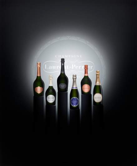 Six bouteilles de champagne de différentes cuvées alignées sur fond noir, éclairage centré – Fayet Hospitality