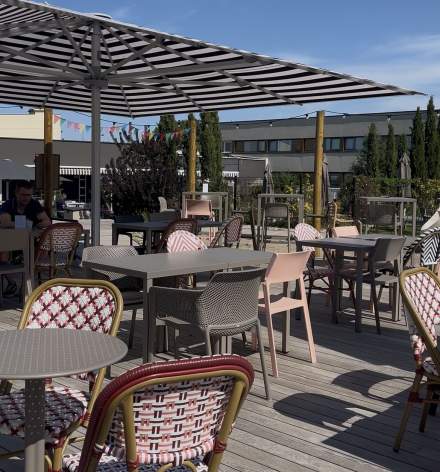 Terrasse extérieure avec tables et chaises bistro sous pergola, espace convivial en plein air, Fayet Hospitality.