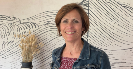 Personne portant une veste en jean et un haut imprimé rouge, fond mural avec motifs graphiques noirs sur fond clair – Fayet Hospitality
