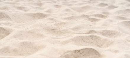 Texture de sable fin aux nuances claires, évoquant plage et détente – Fayet Hospitality