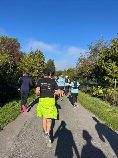 Groupe de coureurs sur un chemin asphalté entouré d’arbres sous un ciel bleu, Fayet Hospitality.