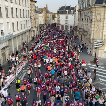 Vue aérienne d’une course urbaine avec des centaines de participants en tenue sportive dans les rues bordées de spectateurs – Fayet Hospitality