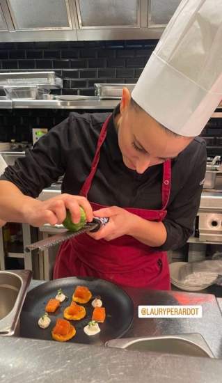 Chef en tenue professionnelle avec toque blanche râpant un agrume sur un plat gastronomique composé de morceaux colorés et crème, dans une cuisine moderne – Fayet Hospitality