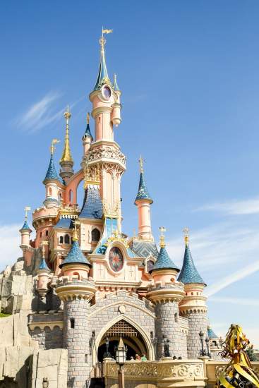 Château féerique de style fantastique à Disneyland Paris sous un ciel bleu clair.