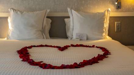 Lit double avec pétales de roses formant un cœur pour une décoration romantique, chambre élégante - Fayet Hospitality