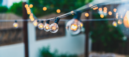 Guirlande de lampes rondes suspendues avec ampoules allumées, créant une ambiance chaleureuse et festive en extérieur - Fayet Hospitality