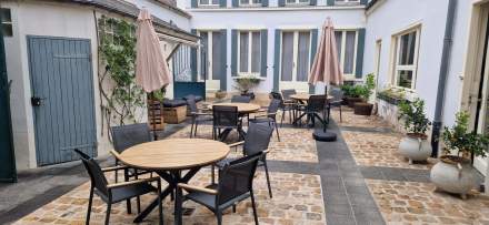 Terrasse pavée avec tables rondes, chaises modernes et parasols, ambiance conviviale – Fayet Hospitality