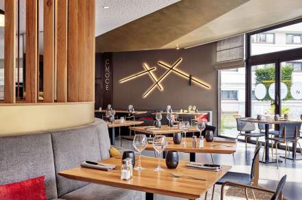 Salle de restaurant moderne du Novotel Collégien Marne-la-Vallée, avec tables élégamment dressées, banquettes confortables et décoration design lumineuse.