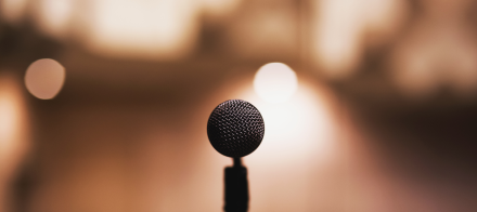 Microphone sur pied en gros plan avec arrière-plan flou et lumière chaude, ambiance élégante pour prise de parole ou événement - Fayet Hospitality